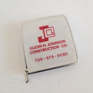 May include: A white tape measure with a red logo that says "Glenn H. Johnson Construction Co. 708-679-9080".