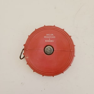 May include: Red measuring tape with a white label that reads "Miller, Bradford & Risberg".