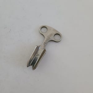May include: A silver-colored metal key with a T-shaped handle and a pointed end. The key has a small hole in the handle and the text "PAT. PEND." is engraved on the side.
