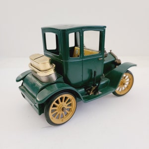 May include: A green toy car with a gold top and yellow wheels. The car has a detailed interior and a back window.