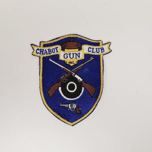 May include: A blue and gold embroidered patch with the text "Chabot Gun Club Inc." and a crossed rifle design.