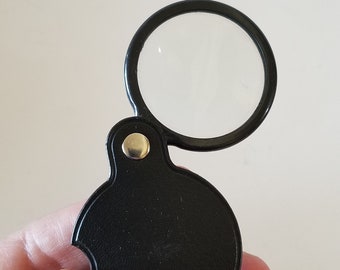 Vintage 1980's pocket magnifying glass, black plastic covered case w/ 1 7/8" diameter, unmarked 5x magnification