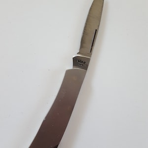 May include: A silver pocket knife with a single blade. The knife has a curved handle and the brand name "Case" is printed on the blade.