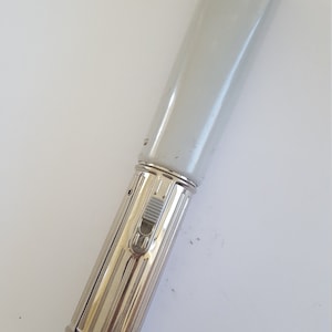 May include: A silver flashlight with a white plastic reflector and a side switch. The flashlight has a ribbed body and a white plastic end cap.
