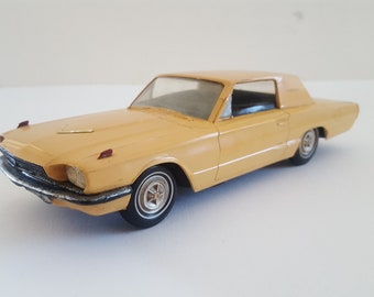 May include: A yellow toy car model of a Ford Thunderbird, a classic American car.