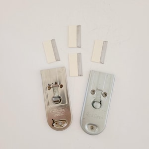 May include: Two metal paint scrapers with replaceable blades. The scraper on the left is labeled "Werner" and the scraper on the right is labeled "Red Devil". Five replacement blades are also shown.