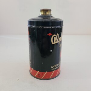May include: A black and red tin can with a gold lid. The can has the text "Alpha Dry" and "Weber Co. Chicago, Ill." printed on it.
