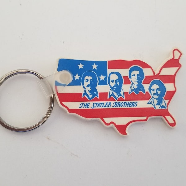 Vintage early 1980's Statler Brothers souvenir keyring vinyl USA shaped fob with the brother floating heads, red, white and blue