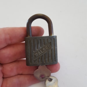 May include: A vintage padlock with a brass finish and a key. The padlock has a  "WALSGO" inscription on the front.