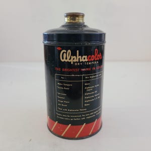 May include: A black tin can with a red and gold label. The label reads "Alphacolor Dry Tempera The Brightest Name in Color". The can contains dry tempera paint.