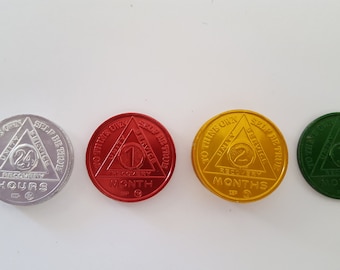 May include: Four silver, red, gold, and green round sobriety coins with a triangle design. The coins feature the text "To thine own self be true" and "Unity, Service, Recovery" with the number of hours, months, or days of sobriety. The coins are 24 hours, 1 month, 2 months, and 3 months.