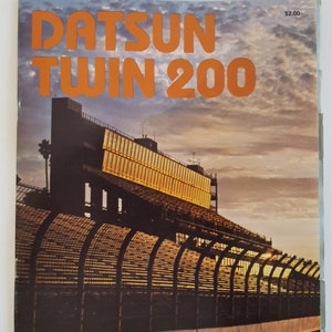 May include: A vintage poster for the Datsun Twin 200 race at Ontario Motor Speedway. The poster features a photo of the racetrack with a large scoreboard and a sunset in the background. The text on the poster reads "Datsun Twin 200", "Ontario Motor Speedway", and "Sunday, March 25, 1979".