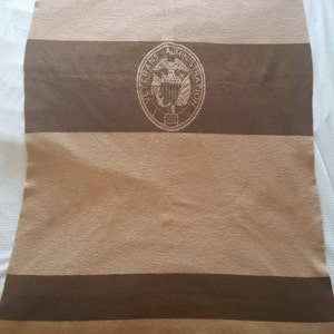 May include: A brown and tan striped blanket with the seal of the Veterans Administration in the center.