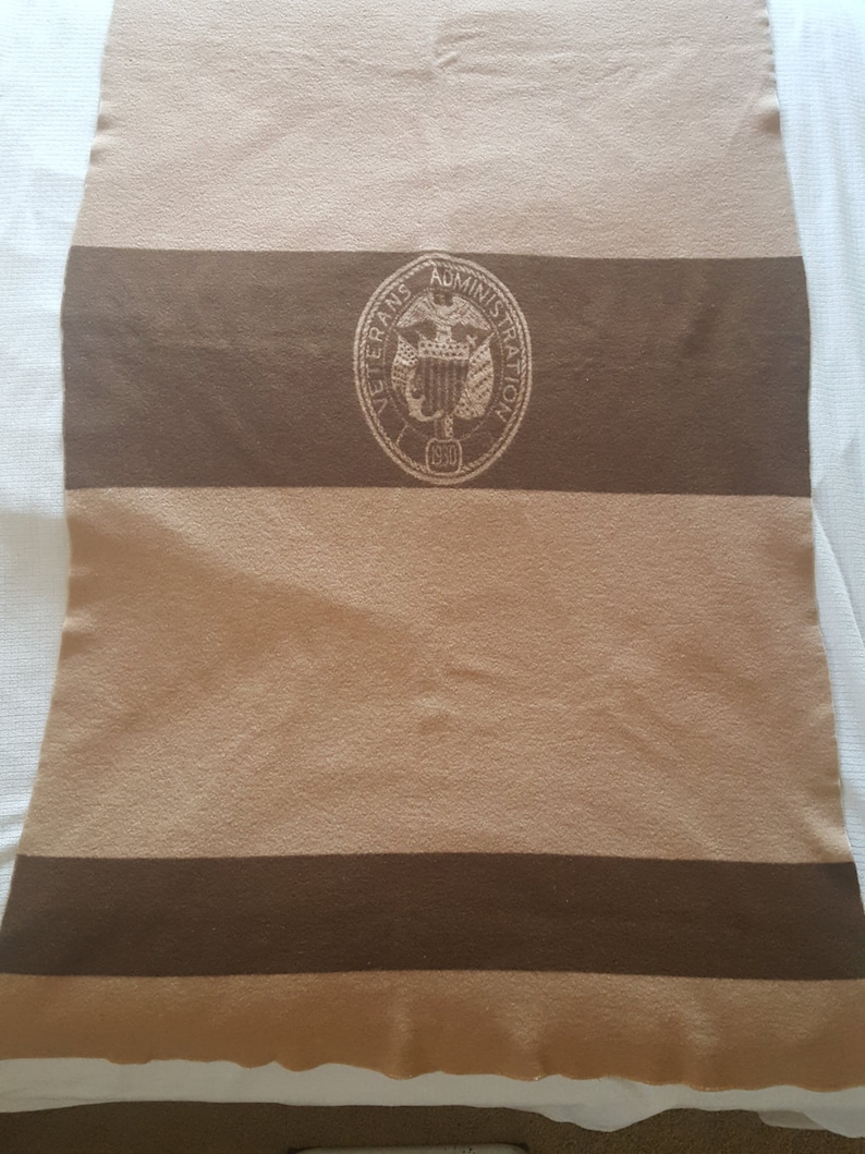 May include: A brown and tan striped blanket with the seal of the Veterans Administration in the center.