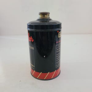 May include: A black metal tin with red and gold stripes around the bottom. The tin has a gold lid and the text "Color" in red lettering. The text "The Original" is also visible on the tin.