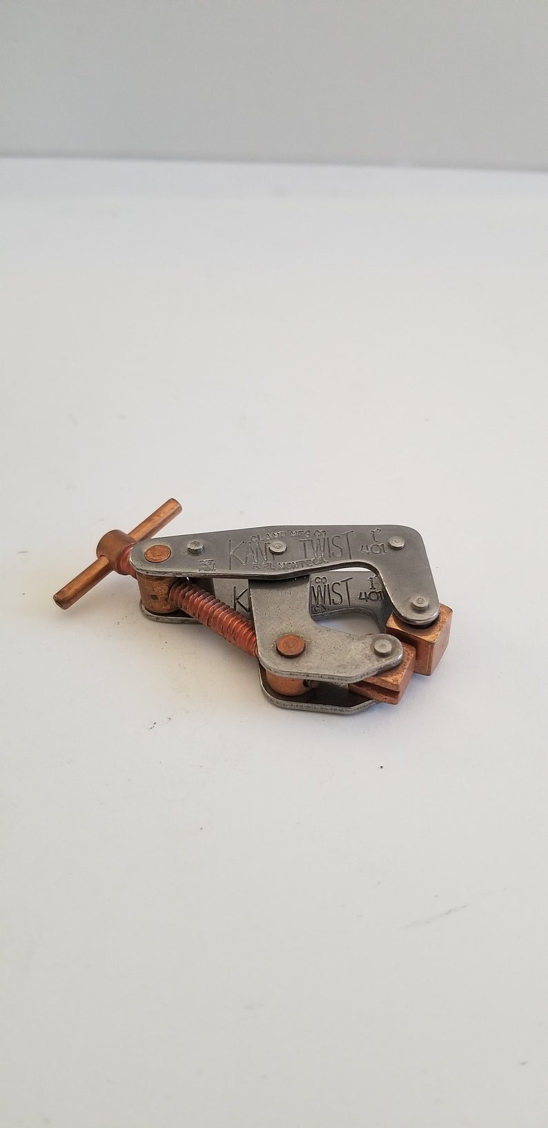 May include: A silver metal clamp with a copper handle and a screw. The clamp is labeled "K&W Twist 1" and "K&W 1" on the side.
