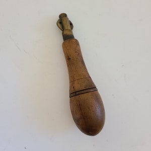 May include: A vintage wooden awl with a brass tip and a wooden handle. The handle is a dark brown color and has a smooth finish.