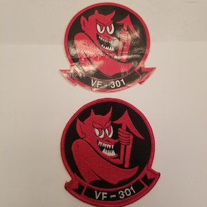 May include: Two red and black embroidered patches with a cartoon devil holding a pitchfork. The patches have the text "VF-301" in white.