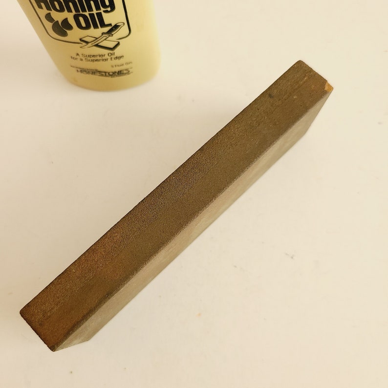May include: A brown rectangular sharpening stone for knives. The stone is made of a coarse grit material.