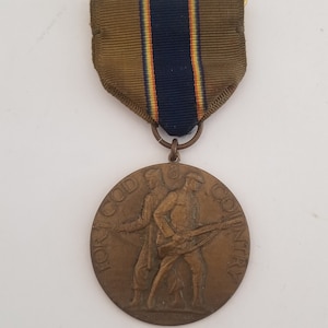 May include: A bronze medal with a ribbon. The medal features two soldiers marching with rifles and the text "For God and Country". The ribbon is brown with a blue stripe and a yellow stripe.
