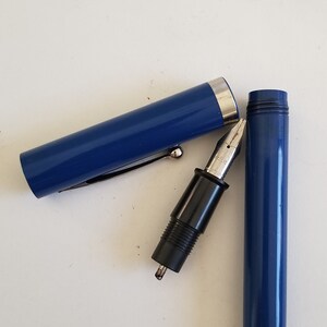 May include: A disassembled blue fountain pen with a silver nib and black grip. The pen's cap and barrel are separated, revealing the pen's internal components. A silver clip is attached to the cap.