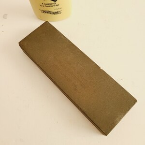 May include: A brown rectangular sharpening stone for honing knives. The stone is made of a coarse grit material.
