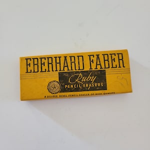 May include: A yellow box with black text that reads "Eberhard Faber Ruby Pencil Erasers" and "A double bevel pencil eraser of high quality".