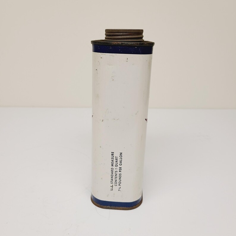 May include: A white metal can with a blue band around the top and bottom. The can has text that reads "U.S. STANDARD MEASURE CONTENT 1 QUART 7 1/2 POUNDS PER GALLON".