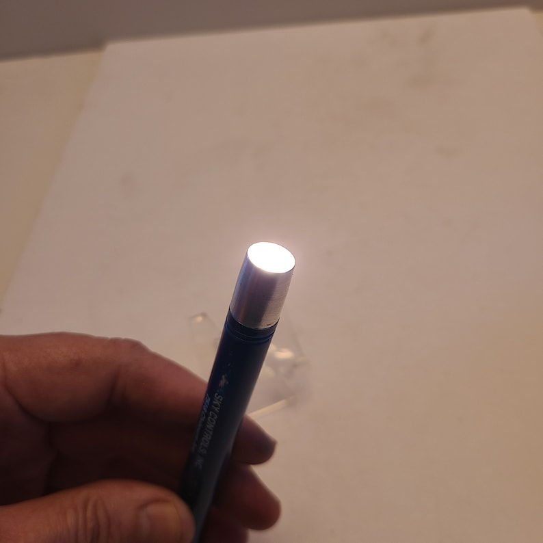 May include: A blue flashlight with a silver head, turned on and illuminating the surrounding area.