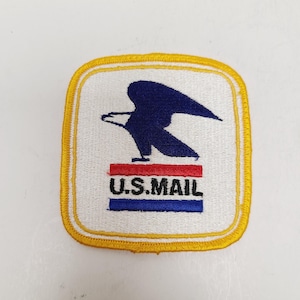 May include: Embroidered patch featuring the U.S. Mail logo. The patch has a white background with a blue eagle emblem above the text "U.S. MAIL" in red and blue. The patch is square with a yellow border.