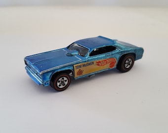 May include: A blue diecast toy car with the words "Tom McEwen" and "Hot Wheels" on the side.