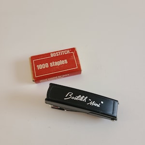 May include: A black Bostitch "Mini" stapler with a red box of 1000 staples that says "chisel pointed for extra stapling power".