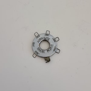 May include: A silver metal spark plug gap gauge with the text "AUTO-LITE SPARK PLUGS" and various measurements in inches.