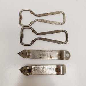 May include: A collection of vintage bottle openers in various designs. Two are loop-style with text, and two are flat, with the text "Schmidt" and "Old Dutch Beer". The openers are made of metal and show signs of age.