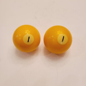 May include: Two yellow billiard balls with the number "1" printed on them.