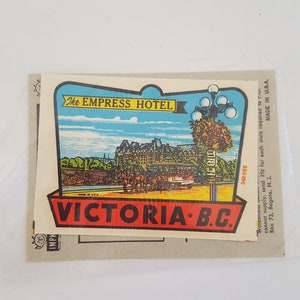 May include: A vintage postcard sticker featuring a colorful illustration of the Empress Hotel in Victoria, British Columbia, Canada. The sticker has a red border with the text "The Empress Hotel" and "Victoria B.C." in black lettering.