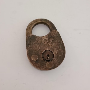 May include: A vintage brass padlock with the words "Eagle Lock Co." and "Eagle" engraved on the front. The padlock has a keyhole and a round shape.