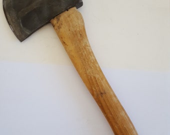 Peut inclure: Une hache à manche en bois avec une tête en métal noir. La hache a un manche légèrement incurvé et un trou à l'extrémité du manche.