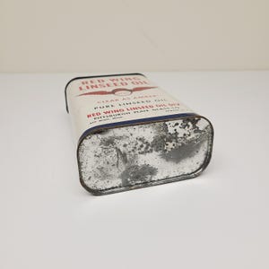 May include: A vintage tin can of Red Wing Linseed Oil. The can is white with red and blue lettering. The text on the can reads "Red Wing Linseed Oil, Clear as Amber, Pure Linseed Oil, Red Wing Linseed Oil Div., Pittsburgh Plate Glass Co., Red Wing, Minn."