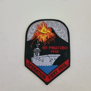 May include: A black and red embroidered patch with a volcano erupting, a ship, and the text "MT PINATUBO 1991 OPERATION FIERY VIGIL".