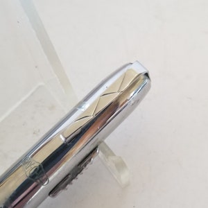 Peut inclure: Un stylo argent&eacute; et dor&eacute; avec un motif textur&eacute; sur le capuchon. Le stylo est sur une surface blanche.