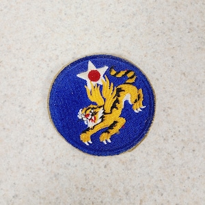 May include: A white ceramic mug with a black handle and the text "But First, Coffee" in a bold, black font. The mug is set against a blurred background, suggesting a cozy setting.