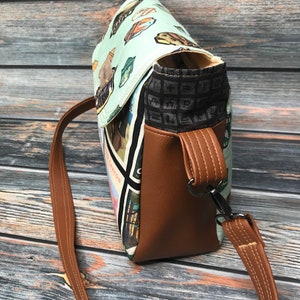 May include: A brown leather crossbody bag with a flap closure and a patterned fabric lining. The bag has a long adjustable strap and a metal clasp.