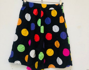 Puede incluir: Falda negra con estampado de lunares de colores. Los lunares son de varios colores, incluyendo rojo, amarillo, verde, azul y rosa.
