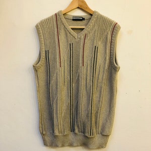 May include: A gray sleeveless sweater with vertical stripes in black, red, and white. The sweater has a v-neck.