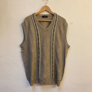 May include: A gray sleeveless knitted sweater vest with a V-neck and vertical stripes of white and green.