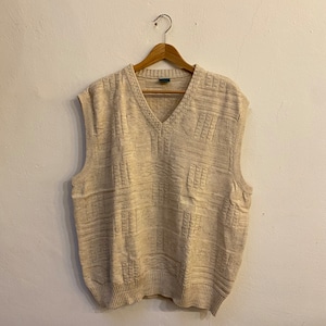 May include: A beige knitted sleeveless sweater vest with a v-neck.