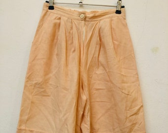 Puede incluir: Culottes de color melocotón de cintura alta con cierre de botón y pliegues en la parte delantera.