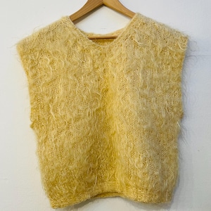 May include: A yellow fuzzy sleeveless sweater knit from a soft, fluffy yarn.