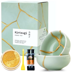 May include: Kintsugi repair kit with gold powder, epoxy, and a yellow spatula. The kit includes two light green ceramic bowls with gold-colored repair lines. The box reads "Kintsugi repair kit" and "Celebrate imperfection by repairing your own ceramics with gold."